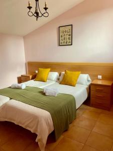 een slaapkamer met 2 bedden met gele en groene lakens bij El Moral Centro de Turismo Rural in Valdecañas