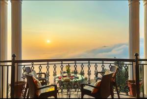 een balkon met een tafel en stoelen op een balkon bij The Horizon Villa Dharamshala in Dharmsala