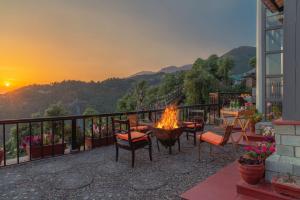 een patio met een vuurplaats op een balkon met uitzicht op de zonsondergang bij The Horizon Villa Dharamshala in Dharmsala