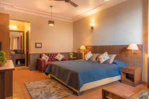 een slaapkamer met een bed en een bank bij The Horizon Villa Dharamshala in Dharmsala +26 foto's
