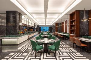 ein Esszimmer mit Tischen und grünen Stühlen in der Unterkunft Wyndham Garden Linxia Downtown in Linxia