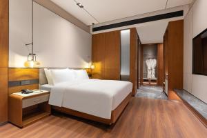 ein Schlafzimmer mit einem großen weißen Bett und einem Fernseher in der Unterkunft Wyndham Garden Linxia Downtown in Linxia