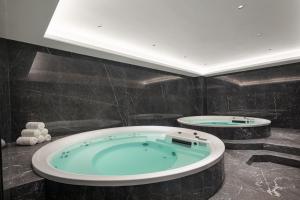 eine Whirlpool-Badewanne im Bad mit schwarzen Fliesen in der Unterkunft Wyndham Garden Linxia Downtown in Linxia + 11 Fotos