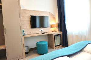 a room with a desk with a tv and a blue stool at Hotel Atlas Halle in Halle an der Saale