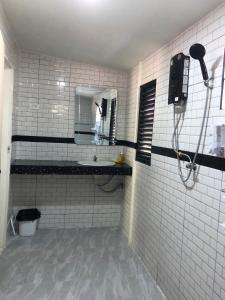 a white tiled bathroom with a sink and a mirror at Lanta Vacation House in Ko Lanta
