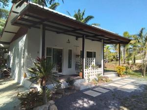a small white house with awning and palm trees at Lanta Vacation House in Ko Lanta