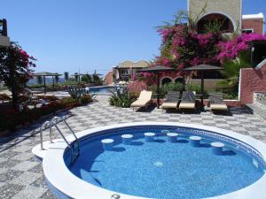 a hot tub in a patio with chairs and flowers at Abelonas Village in Megalochori