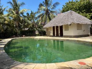 a swimming pool with a building and palm trees at Villa Twiga in Ukunda