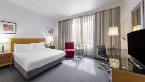 a hotel room with a bed and a flat screen tv at Flagstaff Gardens Hotel Melbourne in Melbourne