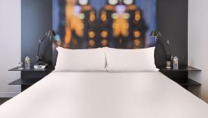 a bed with white pillows and two night stands at Flagstaff Gardens Hotel Melbourne in Melbourne