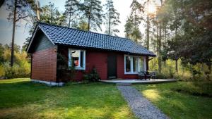 a small red house in the middle of a yard at Host Harmony 6 PP Cabin Close to lake in Vittsjö