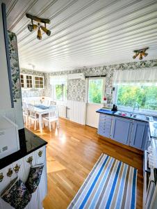 a kitchen with blue cabinets and a dining room with a table at Host Harmony 6 PP Cabin Close to lake in Vittsjö