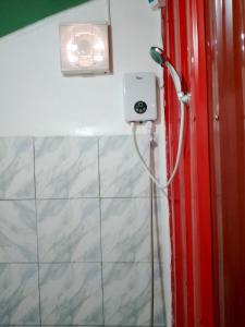 a shower in a bathroom with a red wall at Nory's Tourist Inn in San Vicente