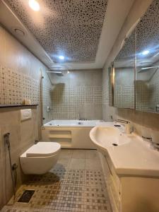 a bathroom with a toilet and a sink and a tub at The Panoramic Centauras in Islamabad