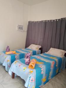 two beds in a room with blue sheets at Nory's Tourist Inn in San Vicente