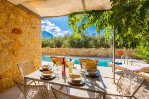 a dining table with chairs and an umbrella next to a pool at Villa Castillo Ena in Agios Nikolaos