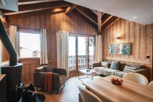 een woonkamer met houten wanden, een bank en een tafel bij Résidence l'Oxalys in Val Thorens