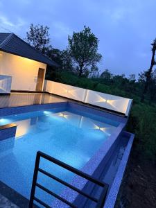 a swimming pool in front of a house at night at Kenza Retreat in Vagamon