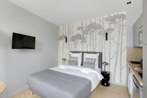 een slaapkamer met een bed en een muur met bomen bij Refined air-conditioned studio in Neuilly in Neuilly-sur-Seine