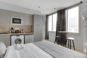 een slaapkamer met een bed en een keuken met een wasmachine bij Refined air-conditioned studio in Neuilly in Neuilly-sur-Seine +3 foto's