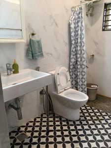 een badkamer met een witte wastafel, een toilet en een wastafel bij Under the Tamarind in Bangalore