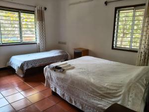 een slaapkamer met twee bedden en twee ramen bij Under the Tamarind in Bangalore
