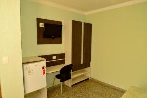 Habitación con silla y TV en la pared. en Residencial Pantanal Santa Cruz, en São Paulo