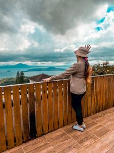 een vrouw die op een houten hek leunt bij Montego Lakeview House with Taal View in Ulot