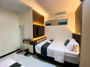 a hotel room with a bed and a television at Kalandra Living in Yogyakarta