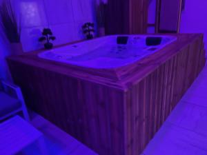 a wooden bath tub in a room with purple lighting at Étoile relax in Douai +2 photos