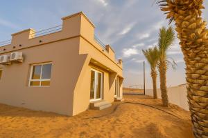 ein Haus in der Wüste mit einer Palme in der Unterkunft Remal Camp in Al Raka