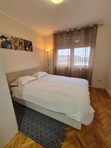una camera da letto con un letto con lenzuola bianche e una finestra di Apartman Srbac a Srbac
