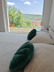 Twee groene kussens op een bed in een kamer met een raam. bij Epic Glamping in Călimăneşti +11 foto's