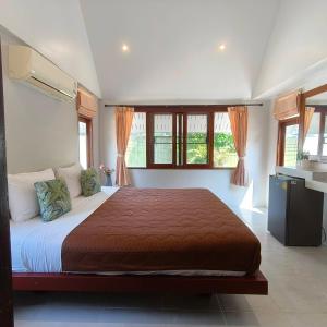 a bedroom with a large bed in a room with windows at Phalarn Inn Resort in Mae Nam