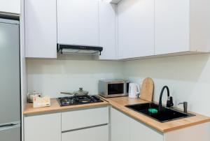een keuken met witte kasten, een spoelbak en een magnetron bij Lavender H in Khujand +12 foto's