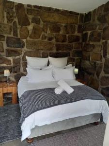 a bed in a room with a stone wall at Springwater Cottages in Ficksburg