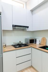 een witte keuken met witte kasten en een magnetron bij Lavender H in Khujand