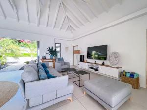 een woonkamer met een bank en een tv bij Sea view beach access path ! in Saint-François