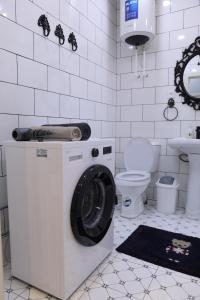 een witte badkamer met een wasmachine en een toilet bij Lavender H in Khujand