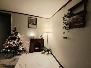 a dog standing next to a christmas tree in a room with a fireplace at Dodahm guesthouse stay in Incheon