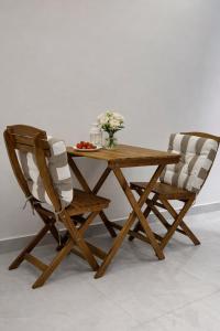 een houten tafel en twee stoelen met bloemen erop bij Abu Rakan Apartment in Muscat
