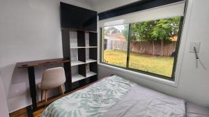 a bedroom with a window and a bed and a desk at Private Room with a view, close to everything in Sydenham
