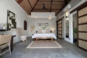 een slaapkamer met een bed, een tafel en een bureau bij Indiana Kenanga Boutique Hotel & Spa in Nusa Lembongan +47 foto's