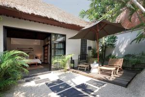 een terras met een parasol en een bed en een slaapkamer bij Indiana Kenanga Boutique Hotel & Spa in Nusa Lembongan