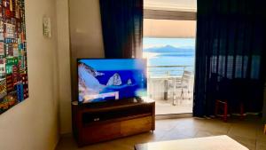 een televisie op een stand in een kamer met een raam bij Sea view studio in Loutraki