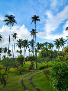 a park with palm trees and a dirt road at Crystal Paradise Resort Spa & Winery in Narra