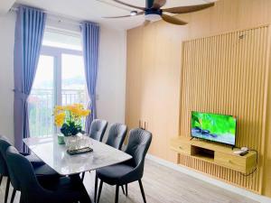 a dining room with a table with chairs and a television at HomeDubai in Kinh Dinh