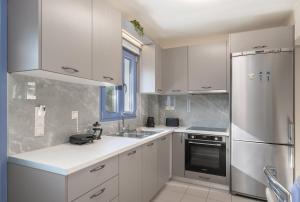 una cucina con mobili bianchi e un frigorifero in acciaio inossidabile di Makis Dream Apartments - Antigoni a Vlachata