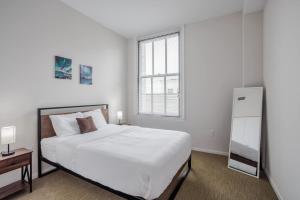 een witte slaapkamer met een groot bed en een raam bij CozySuites Sky Central #20 in Cincinnati