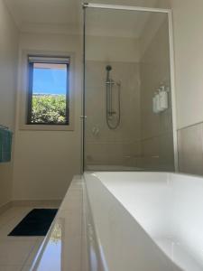 a white bathroom with a shower and a window at Your Leafy Ivanhoe Retreat in Melbourne +13 photos